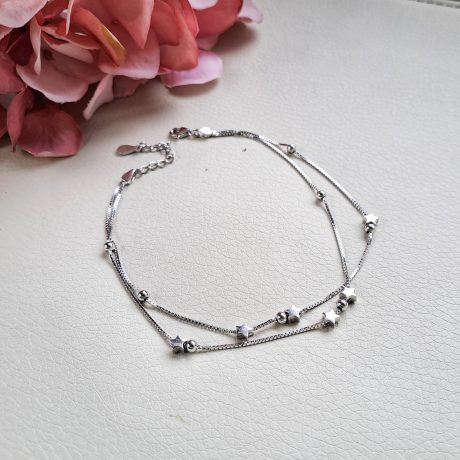Tobillera de plata con doble cadena con seis estrellas y bolitas. 