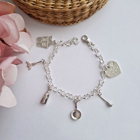 La Pulsera Ama de casa de plata es una pulsera con eslabones redondos entrelazados del que cuelgan  una casita, un plumero, una plancha, una sartén, una escoba y un corazón en el cual esta grabado la frase HOME SWEEL HOME,  con un  sistema de cierre de mosqueton . Características de la pulsera  Pulsera 19 cm Altura casita 18.5 mm Altura plumero 17.6 mm Altura plancha 16.4 mm Altura sartén 18.5  mm Altura escoba 16.4  mm Altura corazón 15.4 mm Plata de ley 925 Descubre la elegante Pulsera Ama de casa de plata con encantadoras joyas inspiradas en el hogar. ¡Hazla tuya y muestra tu estilo!